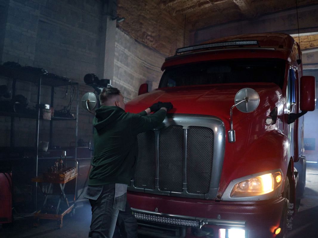 Technician working on the front end of a red semi truck